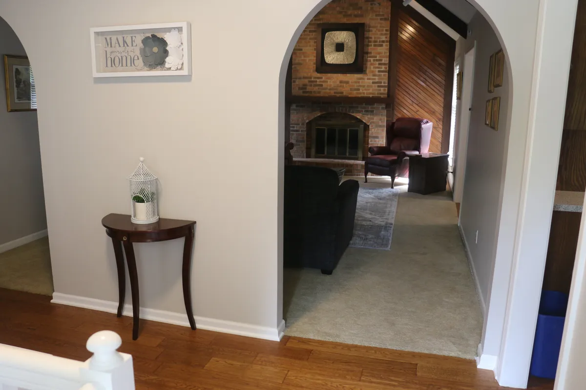 A stylish interior boasting an arched doorway, a central fireplace, a comfortable seating area, and prominent, colorful decorative wall art. The space feels both whimsical and intimate, encouraging exploration and socializing.