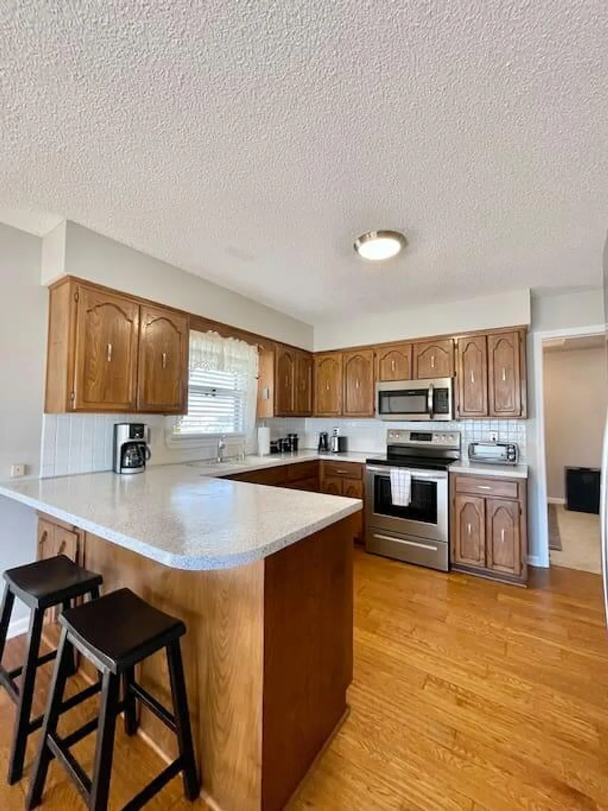 The kitchen features a central island, modern stainless steel appliances, and wooden cabinets. The layout suggests a space designed for both serious cooking and informal gatherings, with ample space for meal prep and socializing.
