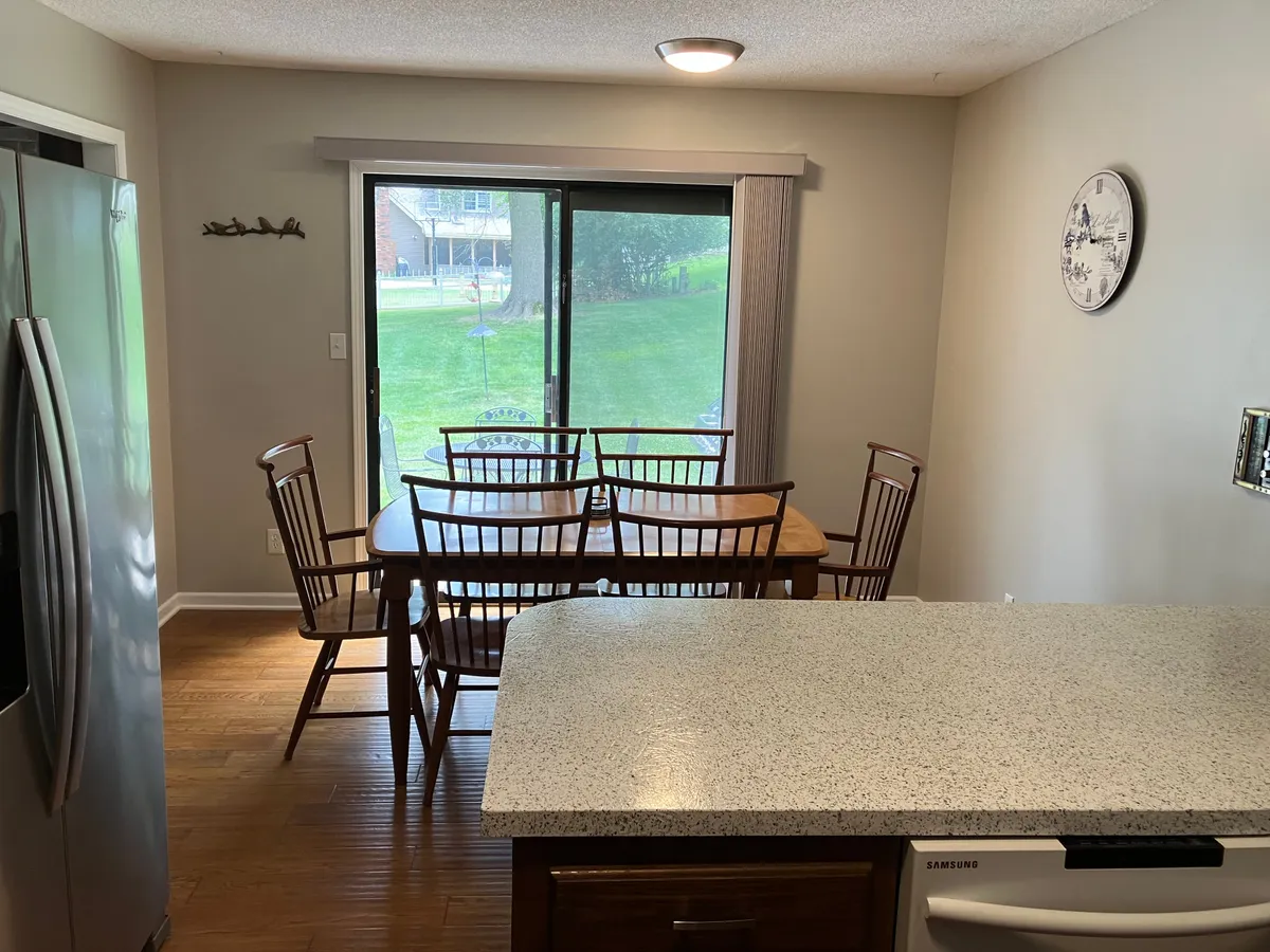 A bright and welcoming dining area with a table and chairs situated near a sliding glass door, offering natural light and a view to the outdoors. The countertop nearby suggests an open-concept living arrangement, ideal for morning coffee or meals.